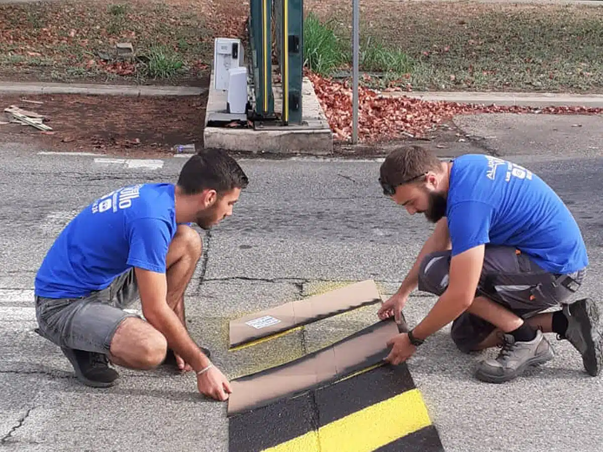 Deux personnes de l’équipe Vullo installant un marquage au sol près d’un portail coulissant.