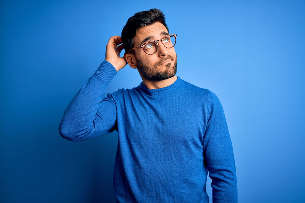 Homme réfléchissant à une solution d’alarme sans abonnement, sur un fond bleu évoquant la tranquillité et la confiance en une sécurité autonome.