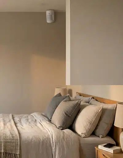 Détecteur de mouvement installé en hauteur dans une chambre moderne, utilisé dans un système d’alarme pour sécuriser un intérieur résidentiel.